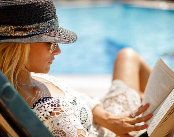 Resident reading a book by the pool at Ellinwood in Pleasant Hill, California