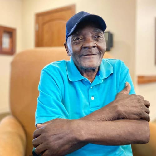 A resident walking smiling and hugging himself at Oxford Glen Memory Care at Carrollton in Carrollton, Texas