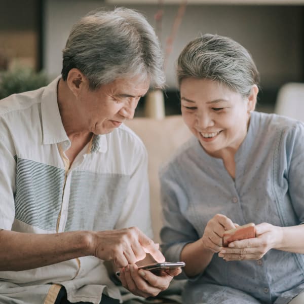 Two residents sitting side by side on their smart phones at Avila Senior Living at Downtown SLO in San Luis Obispo, California