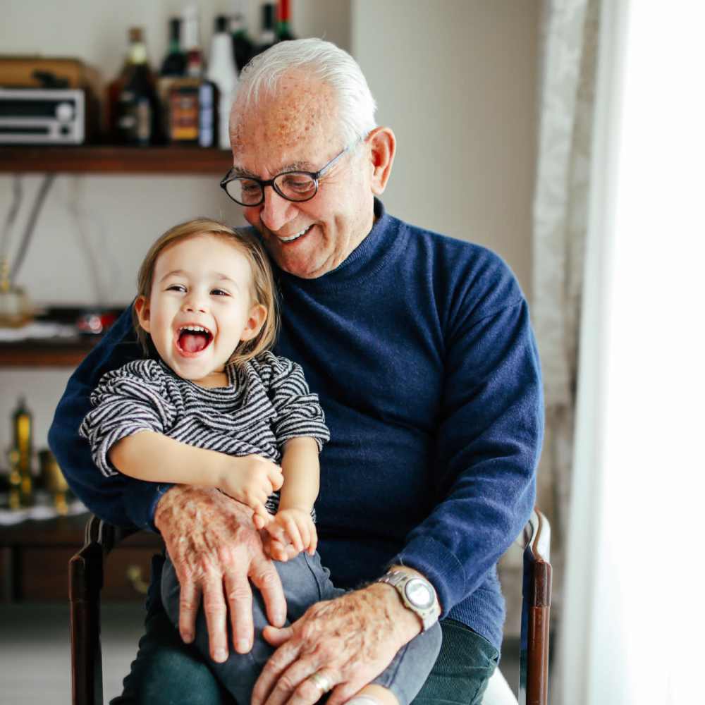 An older man and a little girl sit side by side on a chair at The Lido Apartments in Los Angeles, California