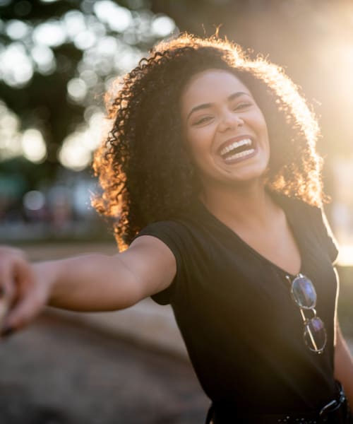 Resident smiling near her new home at Pinebrook Apartment Homes in Fremont, California
