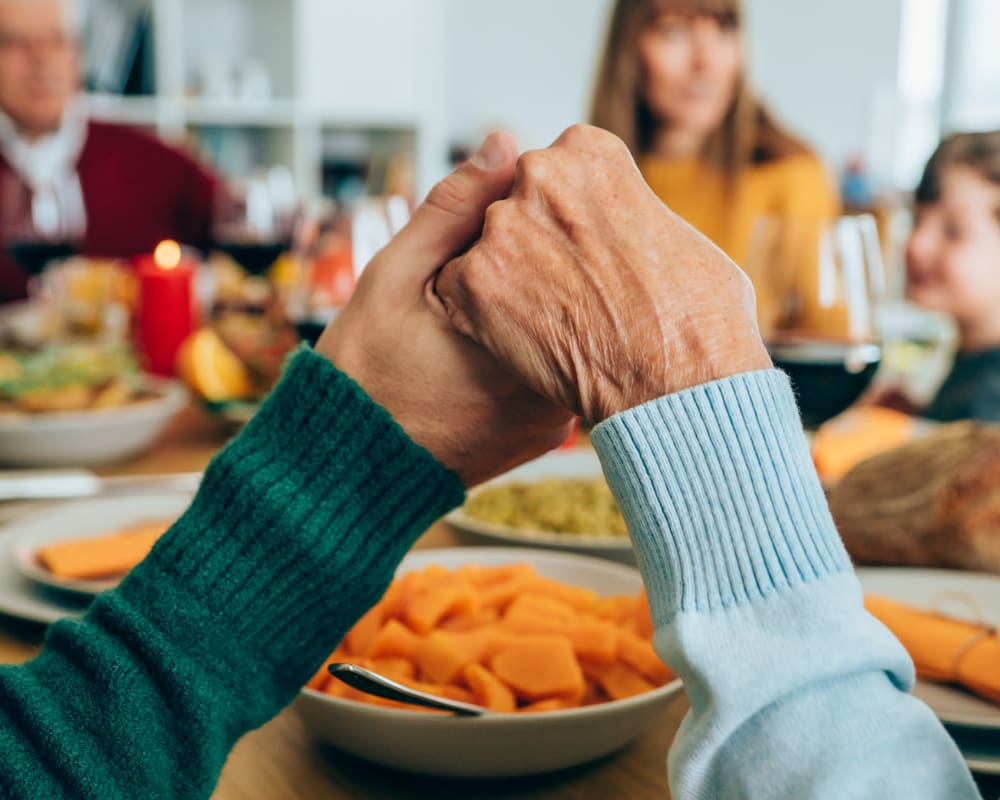 Residents holding hands around a table at Waverly Place in Albany, Oregon