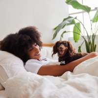 Woman relaxing in bed with a small dog and indoor plants at 43 North Apartments in Grand Haven, Michigan