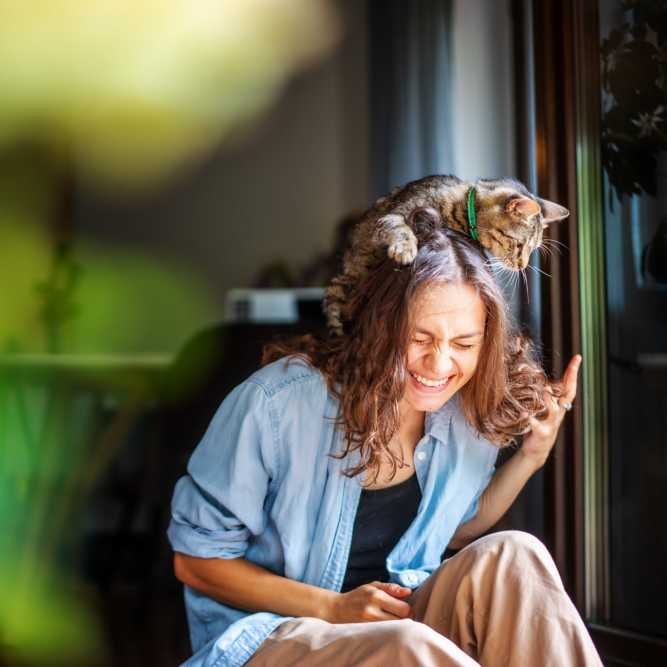 Resident woman laughing with her cat perched on head at Mosby Poinsett in Greenville, South Carolina