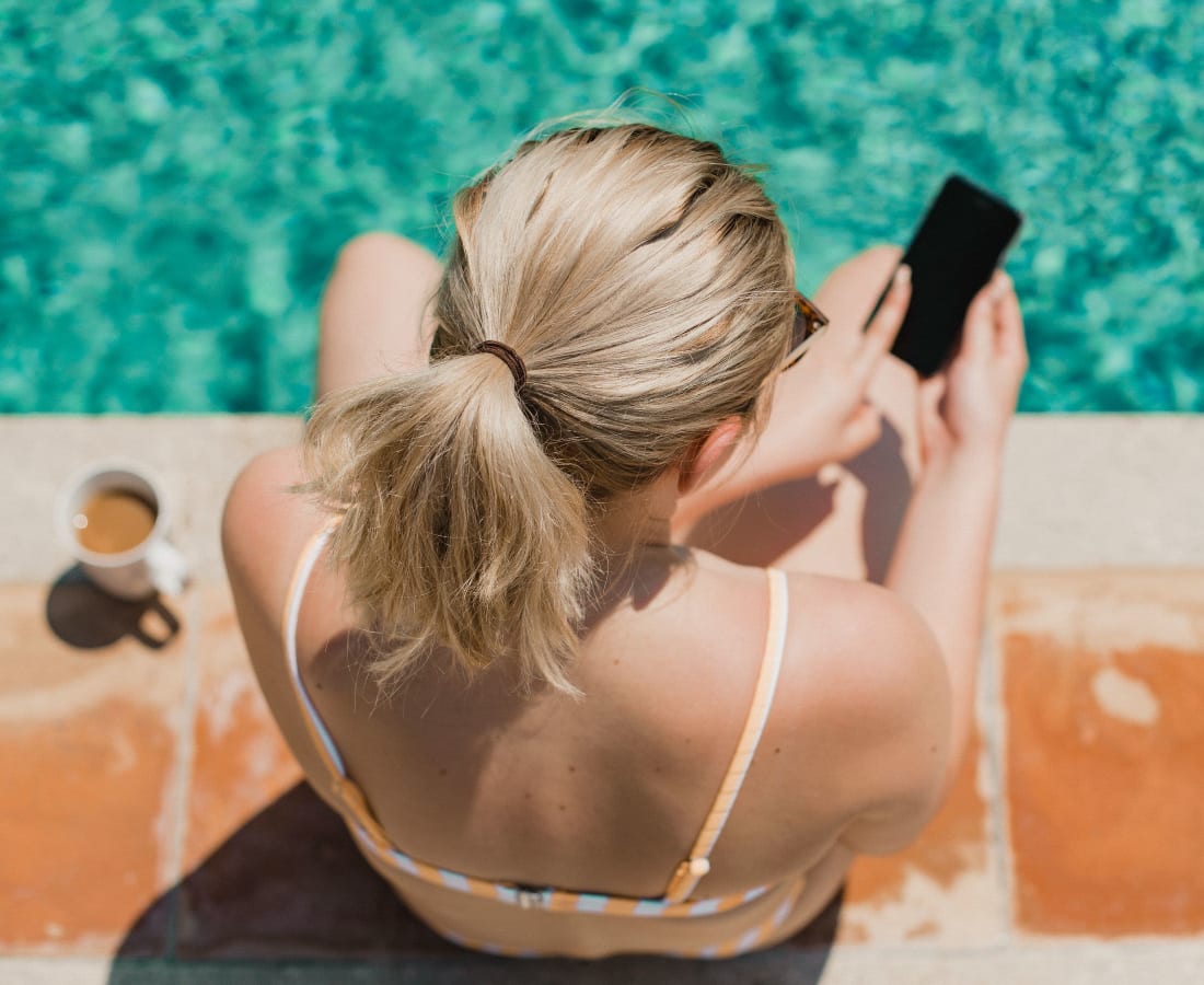 Resident looking at her phone while sitting on the edge of the pool at Hudson at Carolina Forest in Myrtle Beach, South Carolina