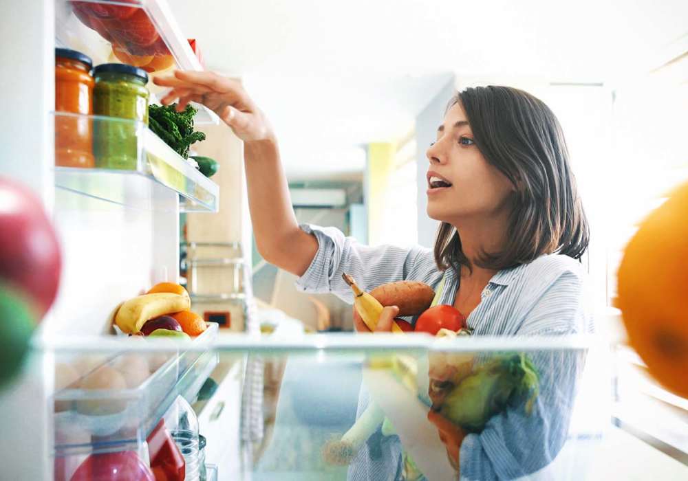 Resident organizing food items in a refrigerator at North Road Townhomes in Scottsville, New York