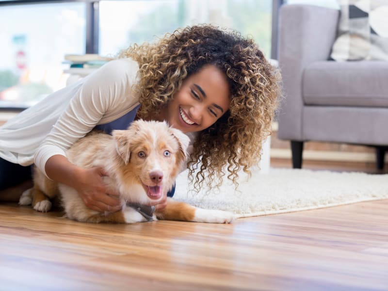 A smiling woman on the floor with her puppy at The Gables in Ridgeland, Mississippi