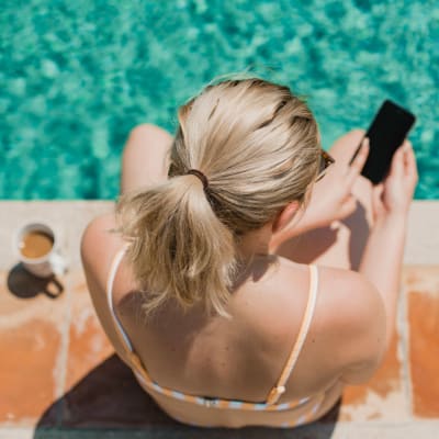 A resident using her phone next to the pool at BB Living at Civic Square in Goodyear, Arizona