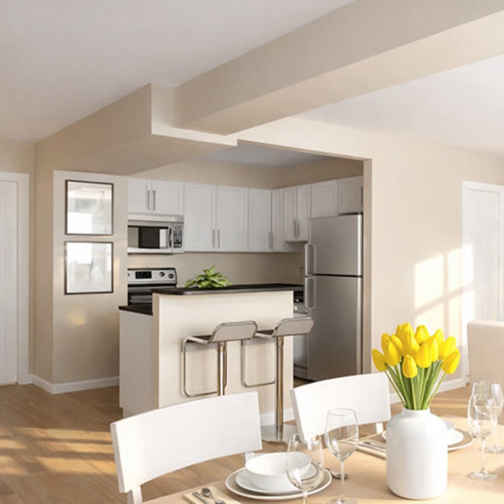 Modern kitchen with stainless steel appliances, granite countertops, and wood-style flooring, dining area with a floral centerpiece at Flats on Fifth in Louisville, Kentucky
