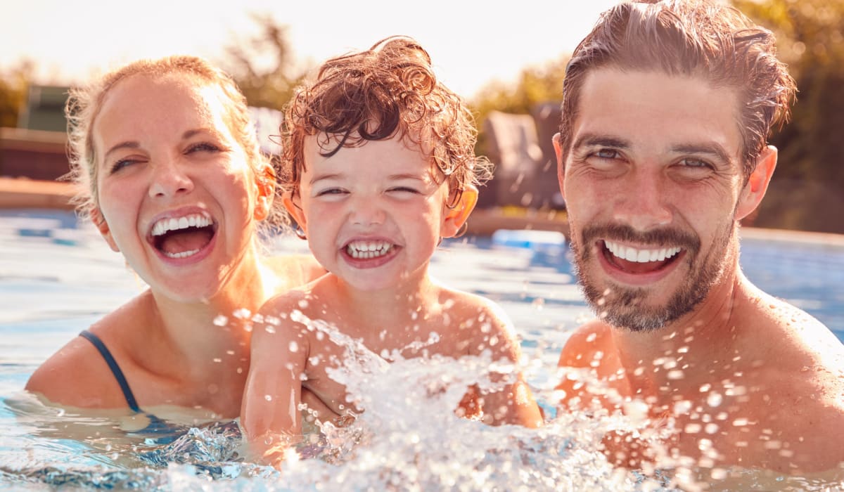 Two parents and a child splashing in the swimming pool at Commons at Briarwood Park in Brookhaven, Georgia