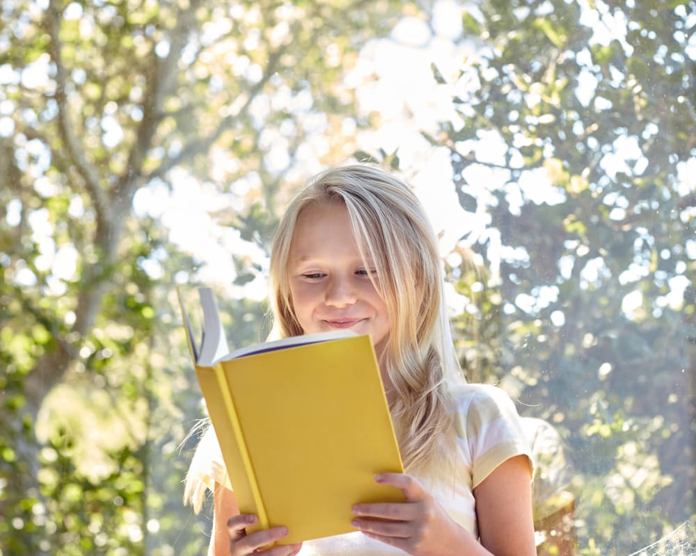 Child happily reading a book in her new home at Sofi at Somerset in Bellevue, Washington