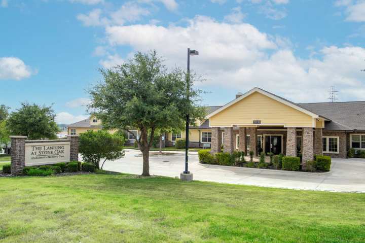 Exterior of The Landing at Stone Oak in San Antonio, TX, featuring a welcoming entrance and manicured grounds, representing trusted memory care in a serene setting.