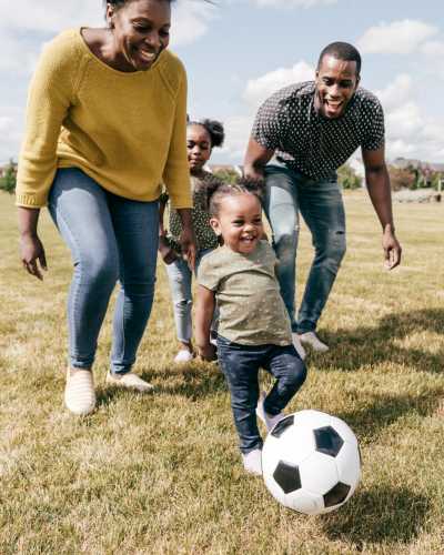 A happy family enjoying a game of soccer in a park near The Fowler in Boise, Idaho