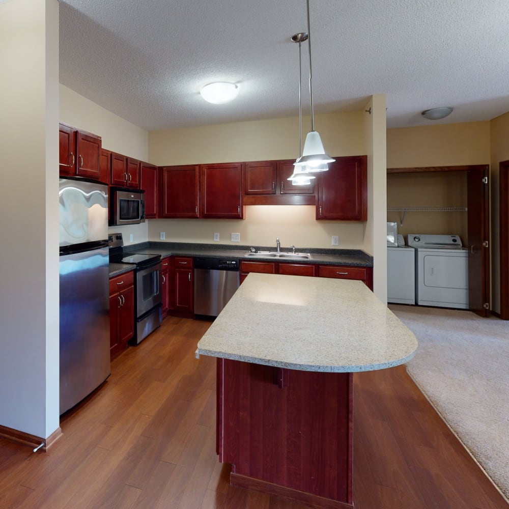 Stainless-steel appliances and an island with bar seating in a model home's kitchen at Oaks Glen Lake in Minnetonka, Minnesota