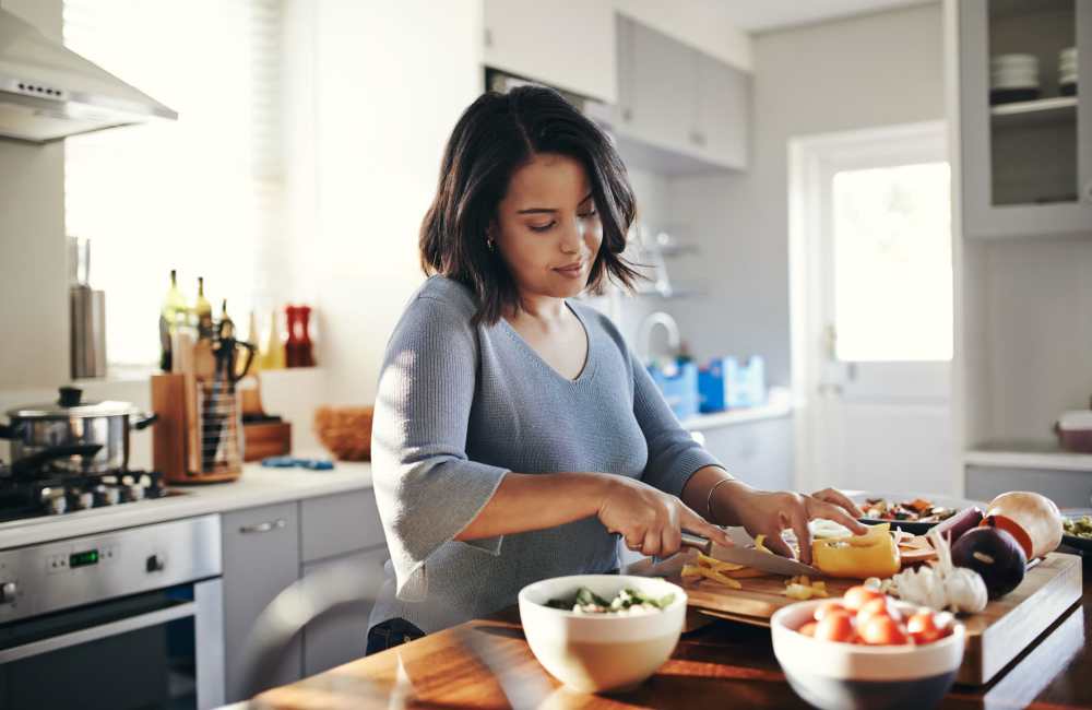 Resident slicing the veggies in the kitchen at Witmer Manor in Los Angeles, California
