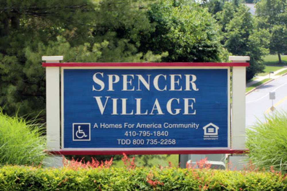 Community sign for Spencer Village surrounded by greenery and colorful landscaping at Spencer Village in Eldersburg, Maryland