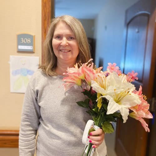 Resident holding flowers and smiling at Oxford Glen Memory Care at Carrollton in Carrollton, Texas