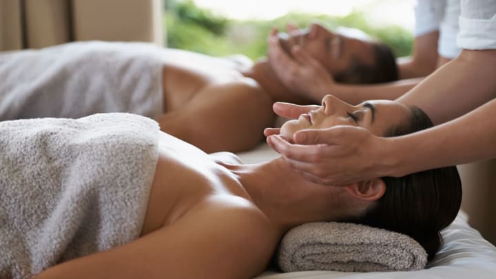 A couple getting a massage wearing white towels.