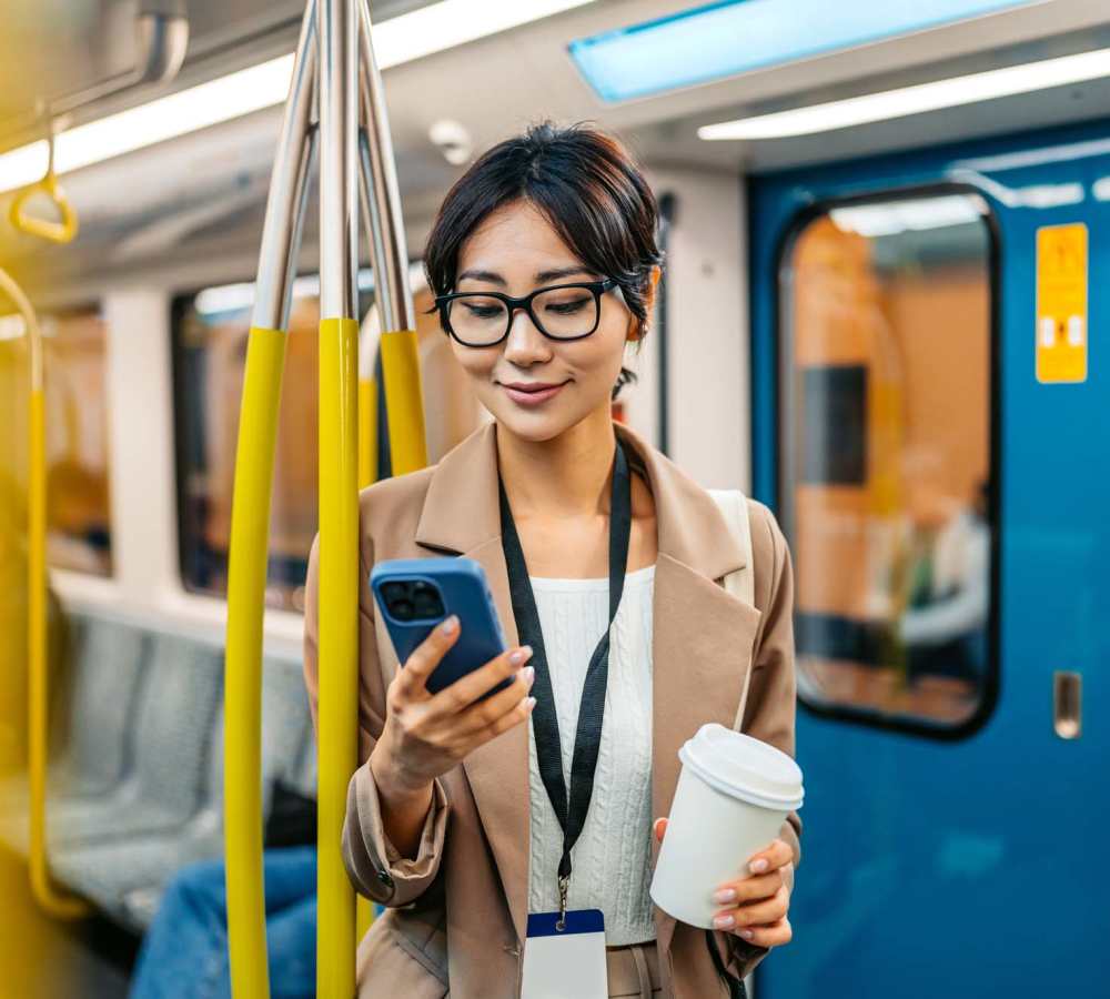 Woman holding a phone and coffee cup at Avia Lofts at Maple Road in Amherst, New York
