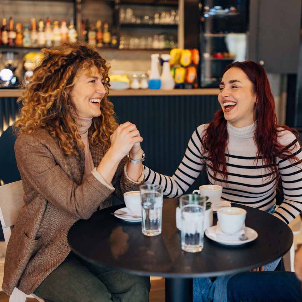 Resident friends sharing a laugh over a meal at their favorite restaurant near Avalon II Apartments in Charleston, South Carolina 