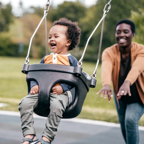 Resident pushing their child on the swings at Farmstead at Lia Lane in Santa Rosa, California