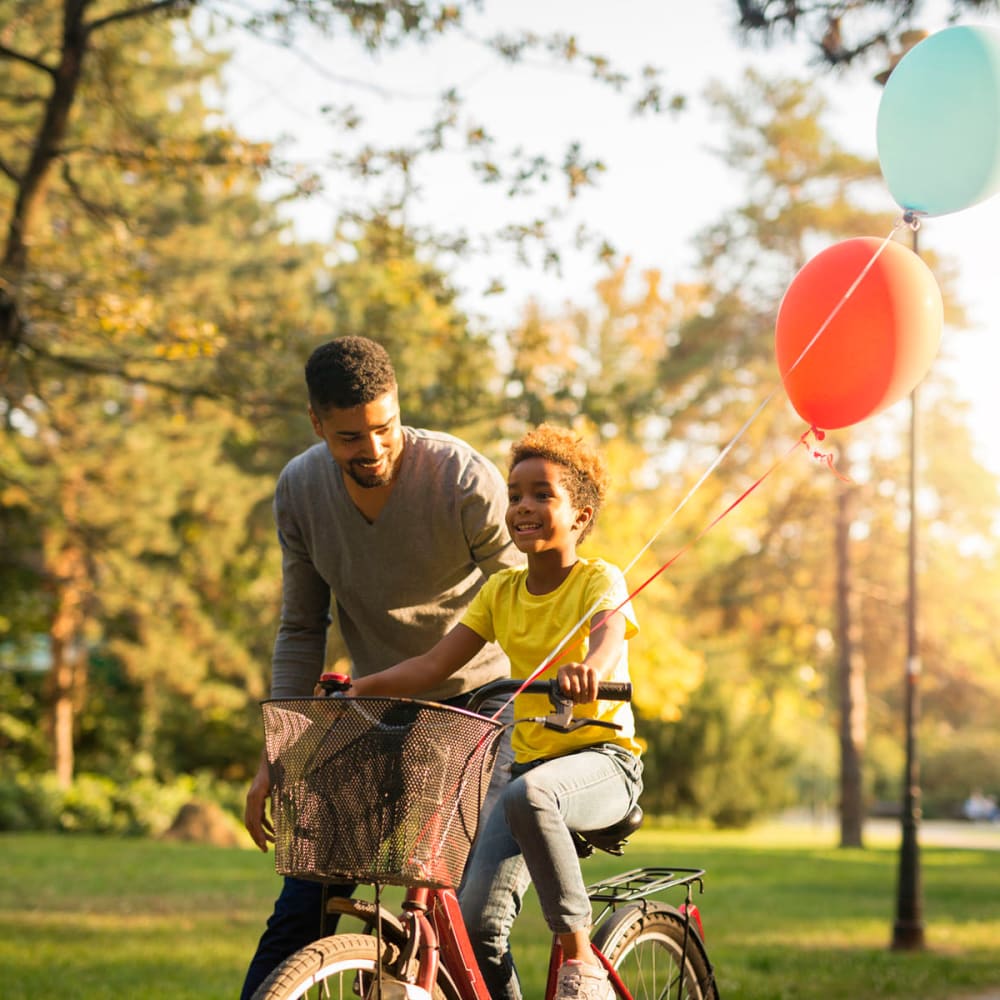 Resident teaching his son to ride a bike through our garden-style neighborhood at Oaks Estates of Coppell in Coppell, Texas