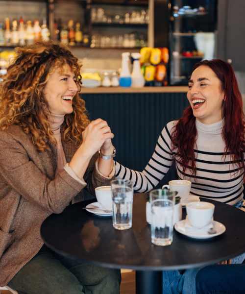 Two woman laughing at a table near Cedar Glen Apartments in Cross Plains, Wisconsin