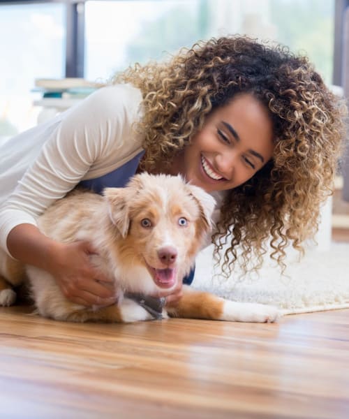 A resident and her pup playing in their home at The Shockoe Collection in Richmond, Virginia