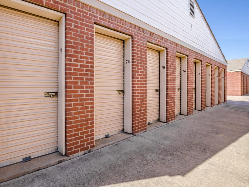 A row of storage units with blue doors and red brick at U-Stor Trinity Mills in Carrollton, Texas