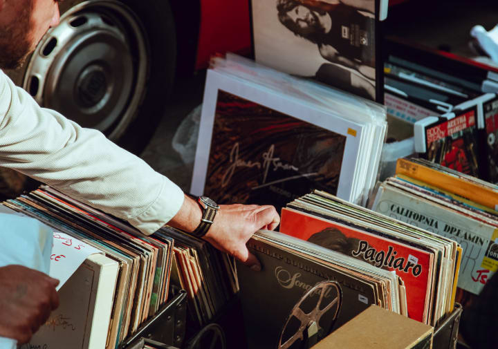 a person looking through a box of vinyl records