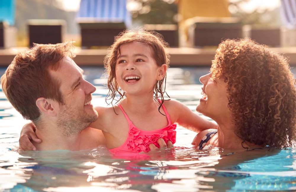 Resident family enjoying in the swimming pool at Lindberg Apartments in McAllen, Texas