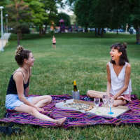 Best friends sharing a laugh in the park near Mount Hope Lofts in Rochester, New York
