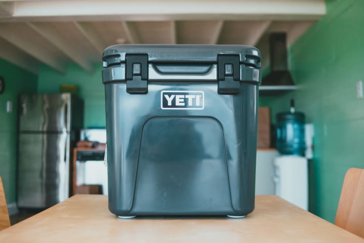 A green yeti brand cooler sits atop a kitchen table in a small apartment kitchen