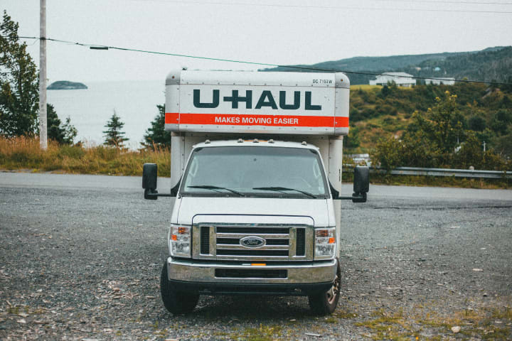 A Uhaul truck sits in the middle of the frame, head on 