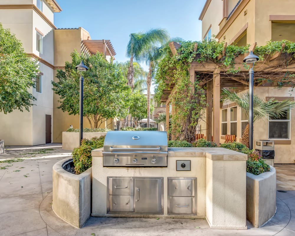 Barbecue area with gas grill and beautiful green flora climbing the buildings nearby at Sofi at Topanga Canyon in Chatsworth, California