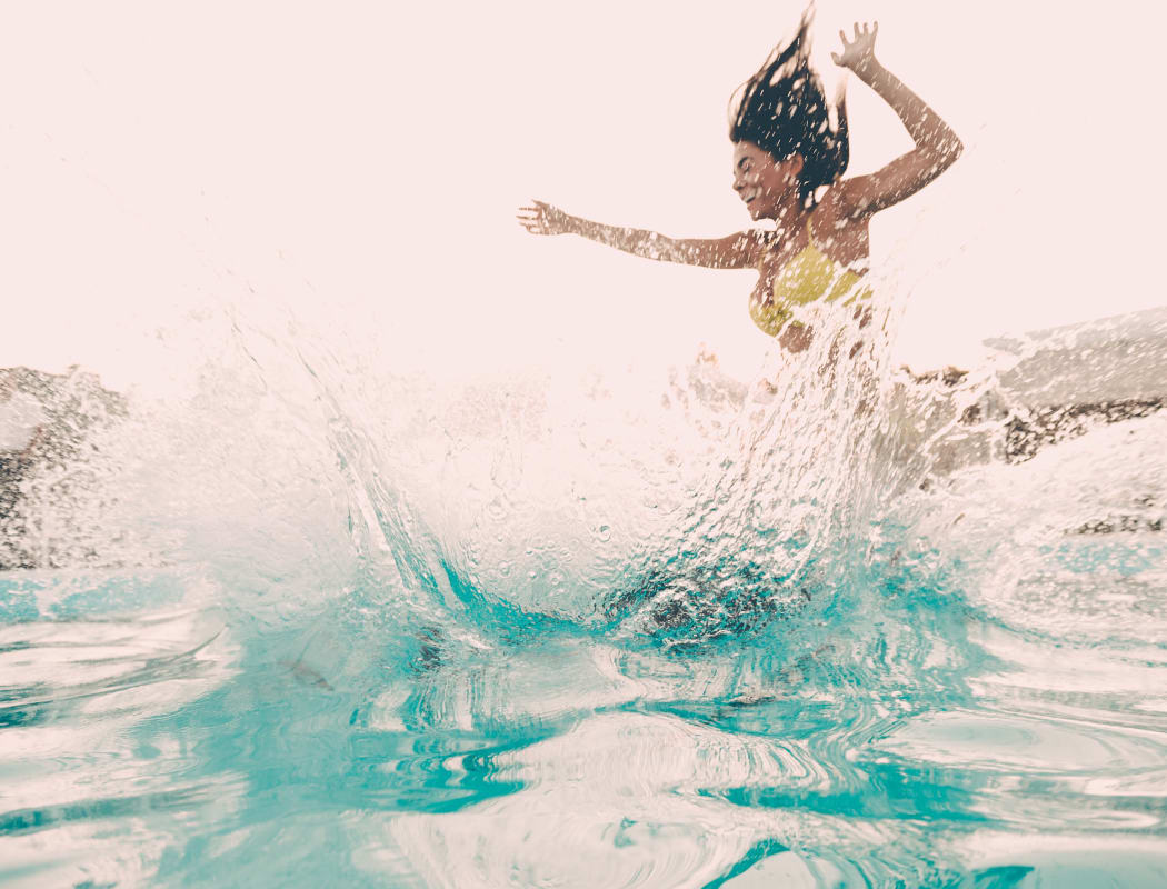 Woman jumping in pool Raintree Apartments in Wichita, Kansas