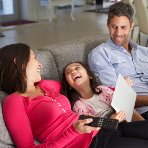 a family laughing on the couch at Covenant Trace in Newport News, Virginia