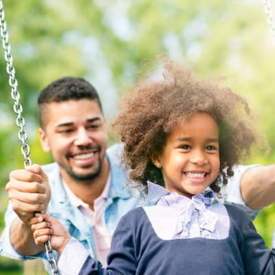 A resident pushing his child on the swings at Carpenter Park in Patuxent River, Maryland