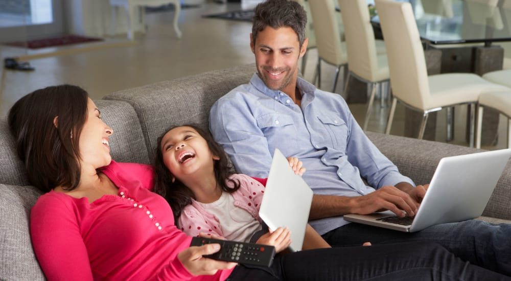 Family hanging out and laughing together on the couch at City View in Lansing, Michigan