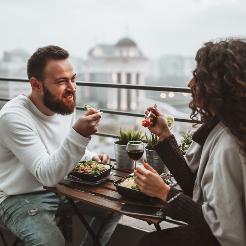 Resident and his guest enjoying an afternoon meal on his private balcony at Anden in Weymouth, Massachusetts