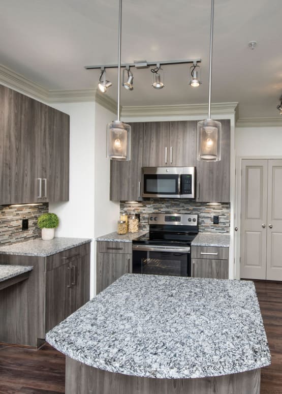 Modern kitchen with stainless-steel appliances and granite countertops in a model apartment at The Heights at Sugarloaf in Duluth, Georgia