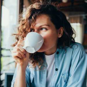 Resident woman having coffee at a cafe near Creekside At Legacy in Plano, Texas