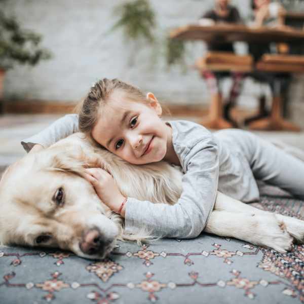 A girl cuddling a large, light-colored dog in her living room at Cypress Pointe in Crown Point, Indiana