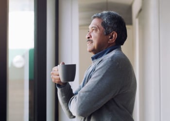 Man looking out the window with his coffee at Whitman Villa Townhomes and Apartments in Hayward, California 