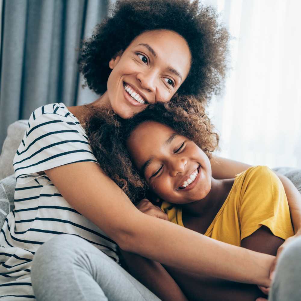 A woman and her daughter sitting on a couch, smiling at each other at Comstock in Bozeman, Montana