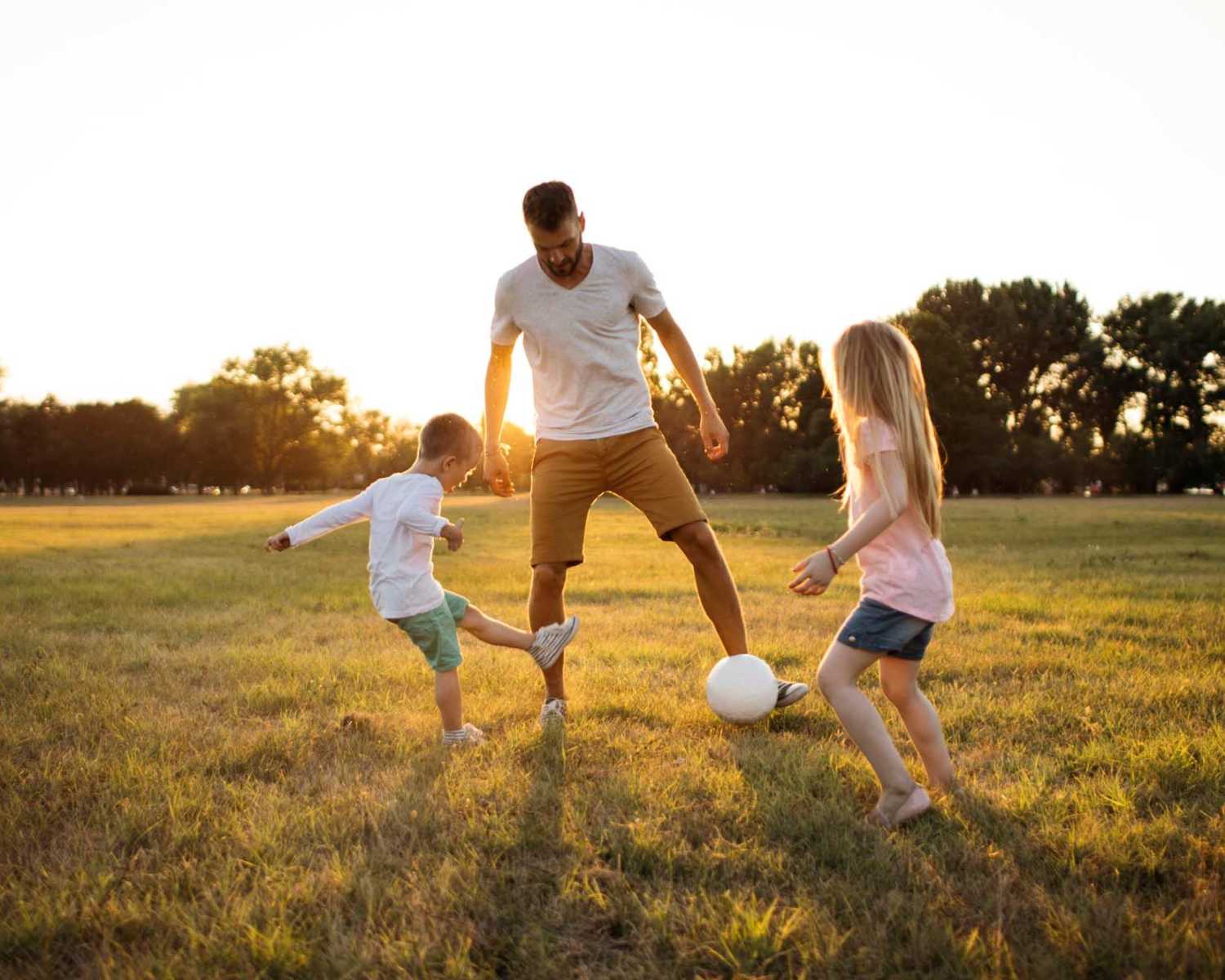 Father playing soccer with son and daughter near Windsor Gardens Apartments in Frederick, Maryland