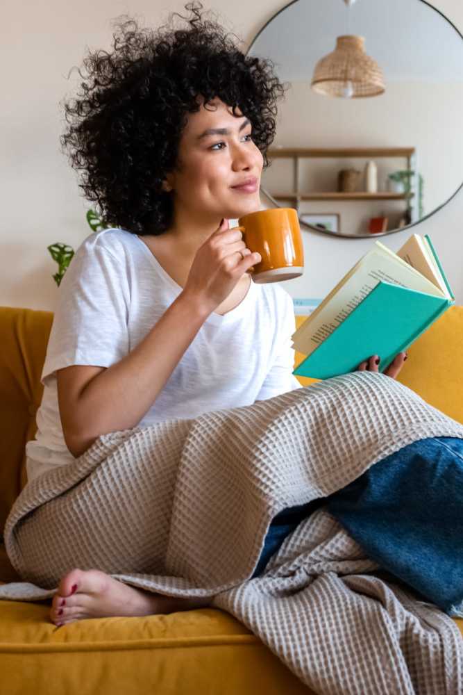 Resident drinking coffee while reading a book in her living room at Pinyon Apartments in Reno, Nevada