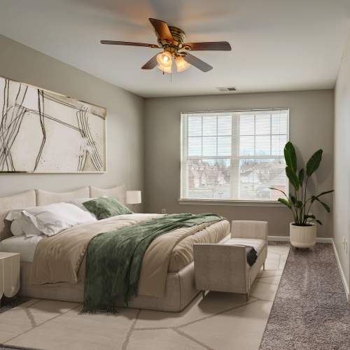 Staged bedroom with ceiling fan, large window, and wall to wall carpeting at Webster Green in Webster, New York