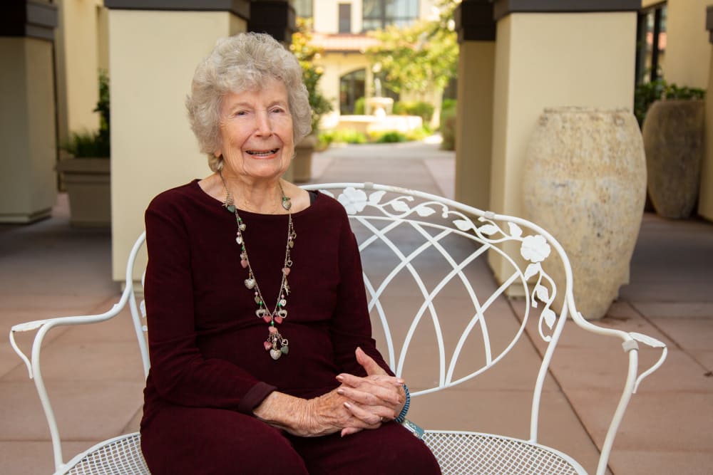 resident smiling in the courtyard at Merrill Gardens at Campbell in Campbell, California
