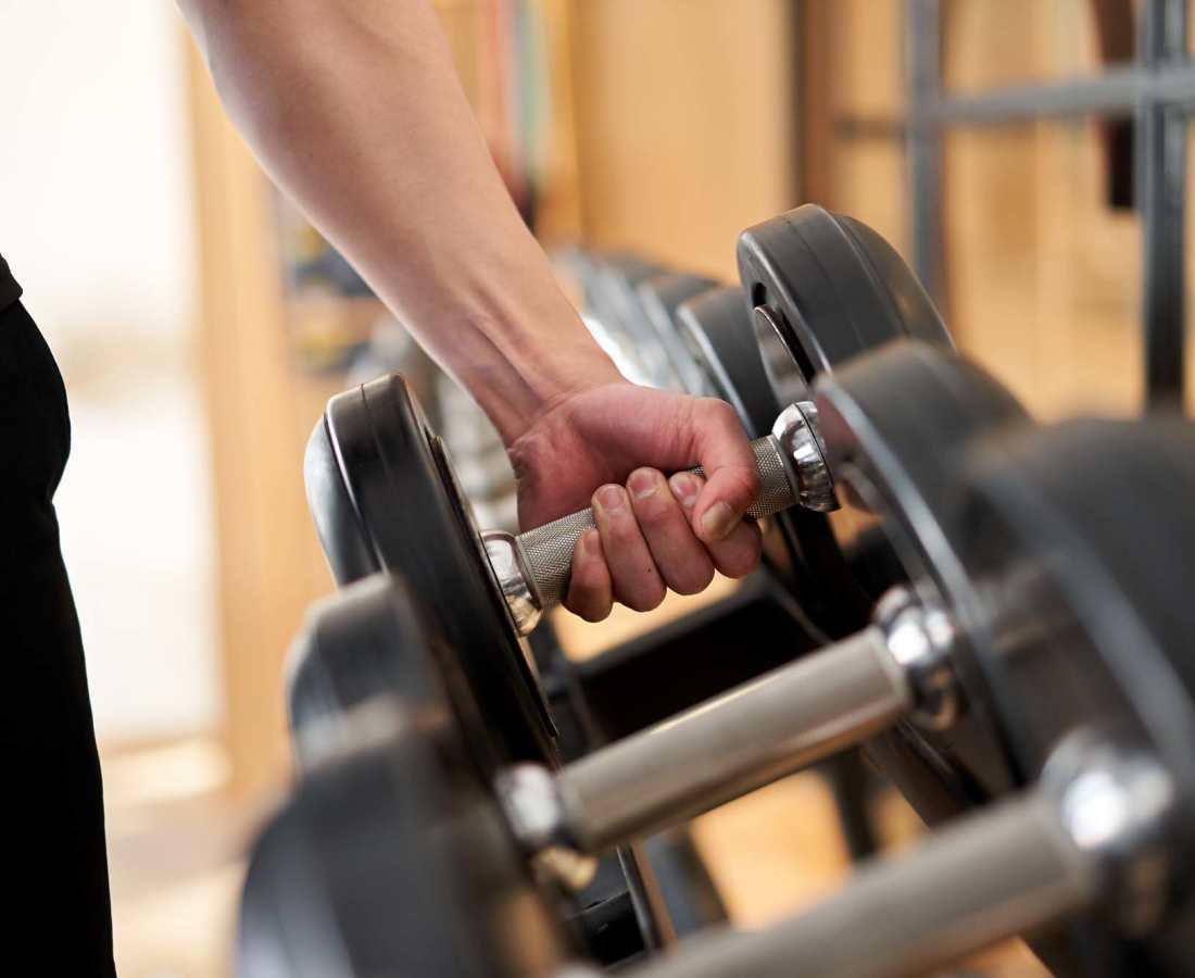 Hand lifting a dumbbell in a modern fitness center with wood-style flooring at Magnolia Park Apartments in Houston, Texas
